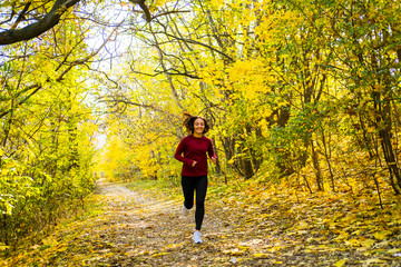 Obraz premium Young happy woman runner training in sunny autumn park