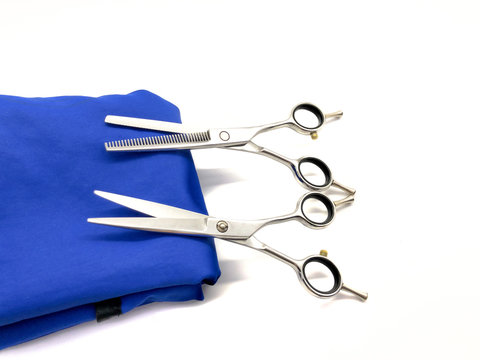 Blue cloak for haircuts, thinning scissors and professional scissors isolated on white background. Set real hair scissors. Hair cutting tools. Hairdressing tools for a beauty salon.