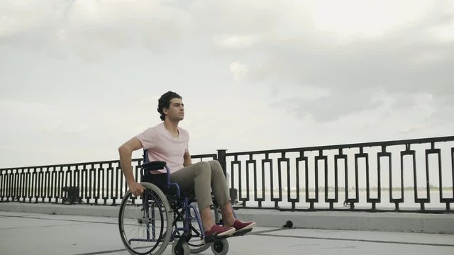 The invalid man sit in the wheelchair rides along the embankment