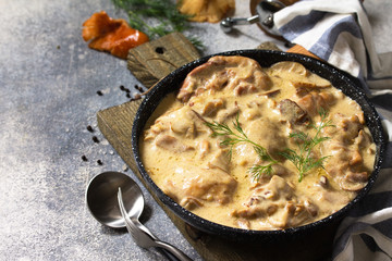 Fricasse - French Cuisine. Chicken stewed in a creamy sauce with mushrooms in a pan on a light...