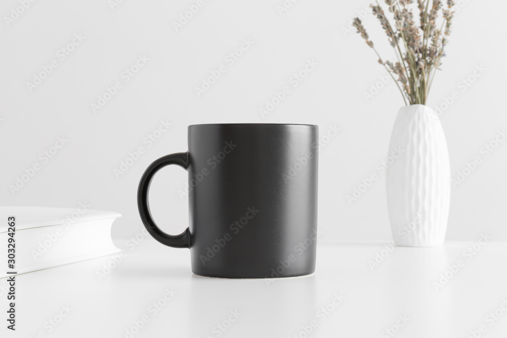 Wall mural black mug mockup with a lavender in a vase and a book on a white table.