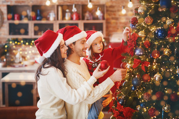 Excited young family making Christmas tree together