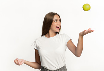 Girl Throwing Apple In The Air Standing Over White Background