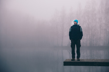 Man standing on a deck above a misty lake. Depression and suicide concept. © belyaaa