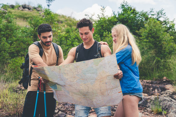 Group of friends hiking with backpacks looking at the map find directions to mountain travel