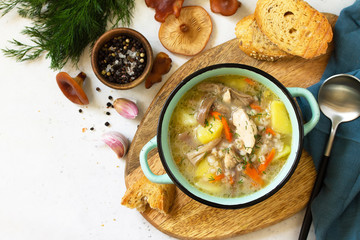 Homemade hot vegetable soup with chicken, mushrooms and bulgur on a white countertop. Top view flat lay background. Copy space.