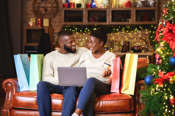 Cheerful afro couple buying Christmas gifts online