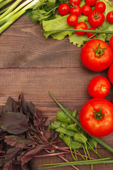 Tomatoes, bellpeppers, lettuce, basil and leek on a rustic table. View from above.