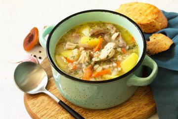 Homemade hot vegetable soup with turkey, mushrooms and bulgur on a white countertop.