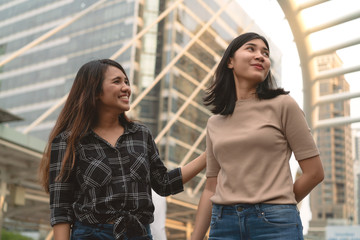 Young diverse pretty Asian girlfriends downtown in urban city - Mixed race girls walking together smiling - Lifestyle social time with millennial best friends - Friendship, hang out and ethnic concept