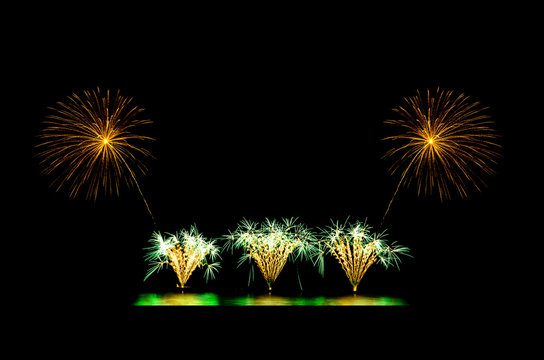 Golden and green fireworks display on black sky with copy space for greeting text. Celebration and anniversary concept