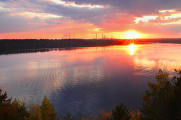 Reflection of the sunset and clouds on the surface of the river. A slight excitement of water on the surface of the river. Reflection of the sunset and clouds in the quiet surface of the river.