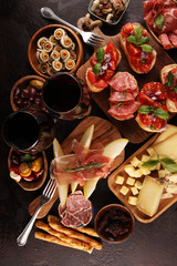 Italian antipasti wine snacks set. Cheese variety, Mediterranean olives, seafood salad, Prosciutto di Parma, tomatoes, anchovy and wine in glasses