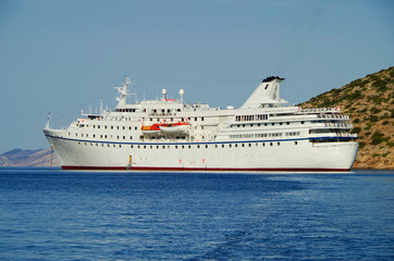 Classic small cruise ship MS Ocean Majesty anchoring in bay on blue sea of Greek Island during...