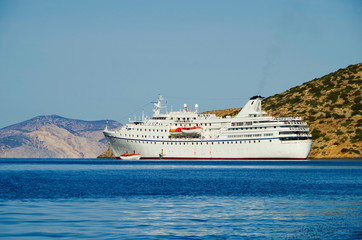 Classic small cruise ship MS Ocean Majesty anchoring in bay on blue sea of Greek Island during...