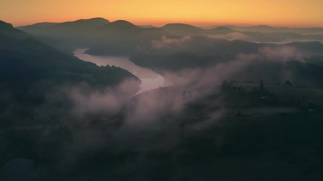 Dramatic sunrise over big river valley with clouds and fog