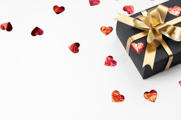 Valentine's Day background. Handmade gift box decorated with red heart confetti on white background. Minimal style and valentines day concept. Flat lay, top view, copy space