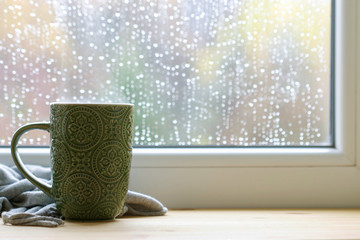 Green mug and soft blanket by the window.