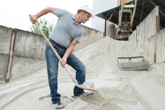 manual worker digging sand with shovel