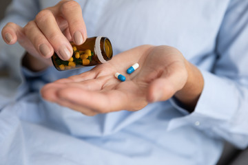 Elderly woman pouring pills from bottle on hand, closeup view