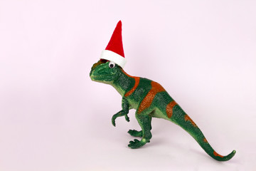 funny green dinosaur toy in little santa claus hat