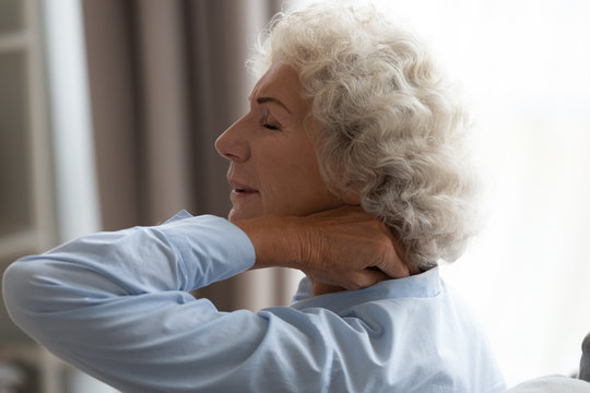 Tired Senior Grandma Rubbing Stiff Neck Suffering From Fibromyalgia Pain