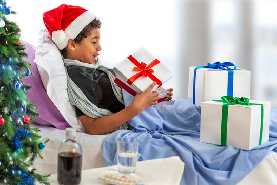 little boy wearing Santa hat receiving her gift while she is in hospital or at home