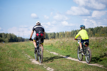 two cyclists ride a country road