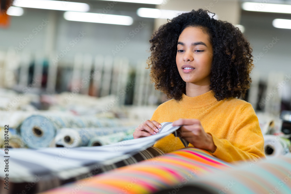 Wall mural smiling woman choosing fabric in textile shop