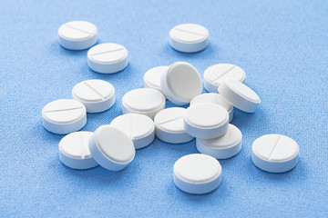 A stack of vitamin and mineral  tablets isolated on a blue background. 