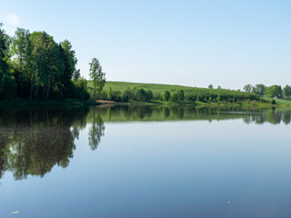 Fototapeta na wymiar beautiful summer landscape with lake and green trees on shore. calm water and reflections