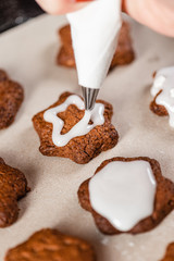 Cooking traditional Christmas sweets. Chef decorates Christmas gingerbread with icing. Close-up.