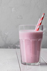 Strawberry protein shake on a white wooden background. Fresh milkshake with strawberries on a light table. A glass of strawberry smoothie.