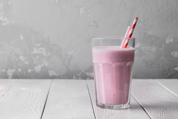 Strawberry protein shake on a white wooden background. Fresh milkshake with strawberries on a light table. A glass of strawberry smoothie.