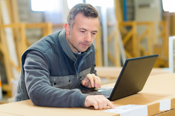 man checking information to enter into laptop computer