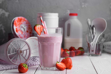 Strawberry protein shake on a white wooden background. Fresh milkshake with strawberries on a light table. A glass of strawberry smoothie.