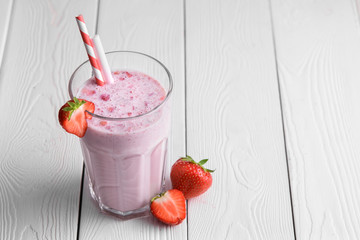 Strawberry protein shake on a white wooden background. Fresh milkshake with strawberries on a light...