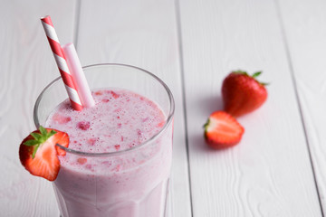 Strawberry protein shake on a white wooden background. Fresh milkshake with strawberries on a light table. A glass of strawberry smoothie.
