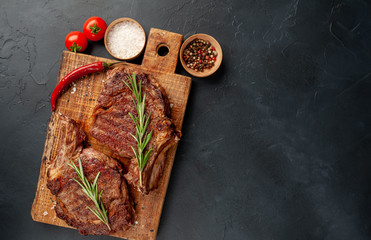 two grilled beef steaks with spices on a stone background with copy space © александр таланцев