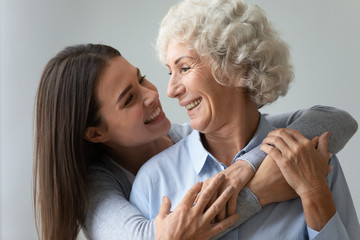 Smiling young woman granddaughter embracing happy old granny or mom