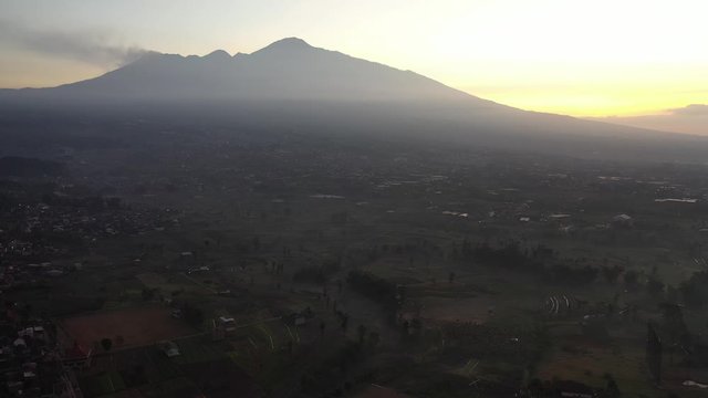Misty sunrise with the Arjuno Welirang, a stratovolcano in province city of Batu in East Java, Indonesia.