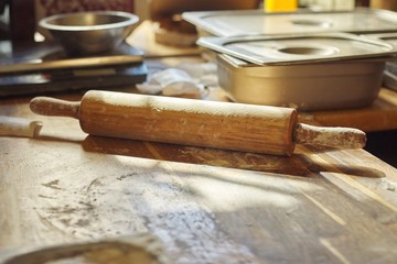 Wooden table in the kitchen with flour, rolling pin dough, nobody