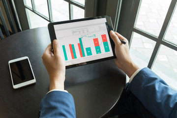 Business man looking to Report Graph visualization from tablet notebook.