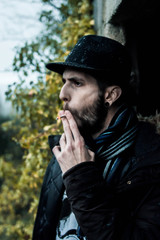 Bearded man and hat looking at the horizon with cigarette