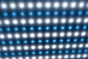 Close-up of a large panel with bright cold blurry lights, luminous buttons in the manufacture of radio products or in a disco. Equalizer and factory equipment concept