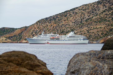 Classic small cruise ship MS Ocean Majesty anchoring in bay on blue sea of Greek Island during...