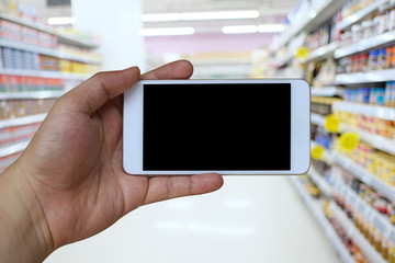Fototapeta na wymiar Hand of a man holding smartphone device in the supermarket background.