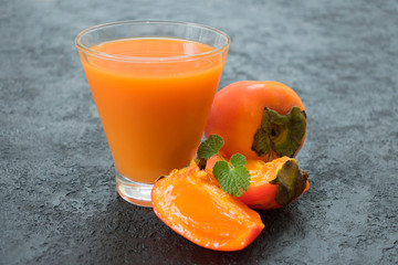  Fresh raw squeezed persimmon juice on a black background. Close-up.