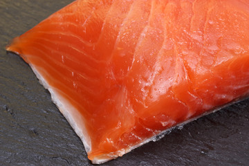 Trout fish fillet macro. Salted piece ready for eat. Fish fillet on slate stone black background plate. Omega 3 healthy food