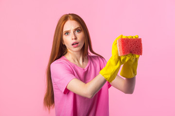 beautiful young woman with red hair in yellow rubber gloves on a pink background